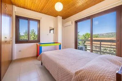 a bedroom with a bed and large windows at The River House in Trimiklini