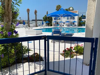 a resort balcony with a pool with a blue umbrella at Alexia Hotel Apartments in Ayia Napa