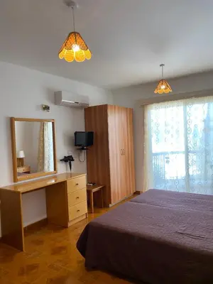 a bedroom with a bed and a desk and a mirror at Alexia Hotel Apartments in Ayia Napa