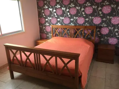 a bedroom with a bed with pink sheets and floral wallpaper at Sea View Apartment in Limassol