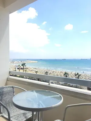 a table and chairs on a balcony with a view of the beach at Alex Beach Apartment 33 in Larnaka