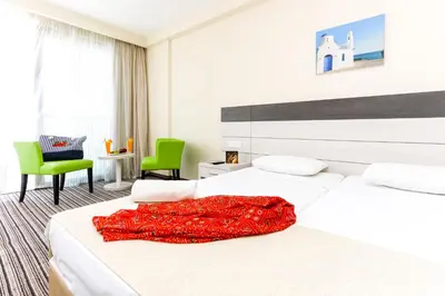 a bedroom with two beds with a red blanket on it at Christofinia Hotel in Ayia Napa