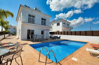 a villa with a swimming pool in front of a house at Nissi Villa Gintare in Ayia Napa