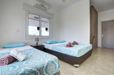 a bedroom with two beds and a window at Nissi Villa Gintare in Ayia Napa