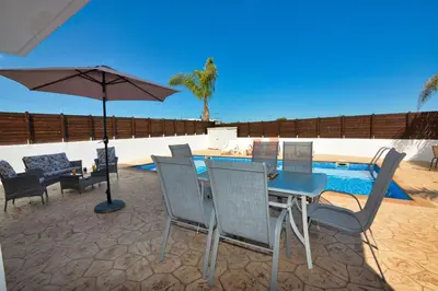 a patio with a table and chairs and an umbrella at Nissi Villa Gintare in Ayia Napa
