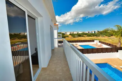 a balcony with a view of a swimming pool at Nissi Villa Gintare in Ayia Napa