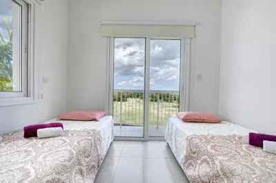 two beds in a white room with a balcony at Nissi Villa Christa in Ayia Napa