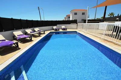 a large swimming pool with chairs at Nissi Villa Christa in Ayia Napa