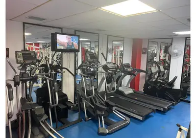 a gym with several tread machines and a flat screen tv at Navarria Blue Hotel in Limassol