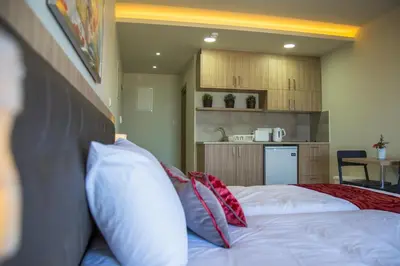a bedroom with a bed with pillows and a kitchen at Zodiac Hotel Apartments in Larnaka