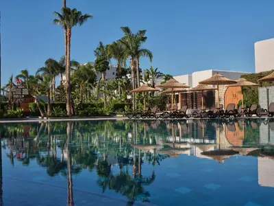 a swimming pool with palm trees and umbrellas at Atlantica Oasis Hotel in Limassol