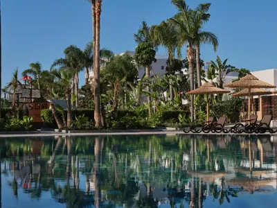 a pool at a resort with palm trees and umbrellas at Atlantica Oasis Hotel in Limassol