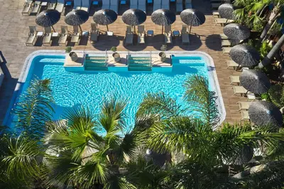an overhead view of a pool with chairs and palm trees at Atlantica Oasis Hotel in Limassol