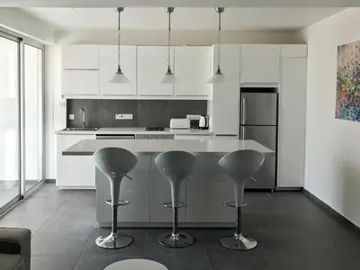 a kitchen with white cabinets and a counter with stools at Poseidon Apartment by Michalis in Ayia Napa