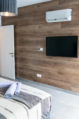 a bedroom with a wooden wall with a flat screen tv at Bayview Terraces in Limassol