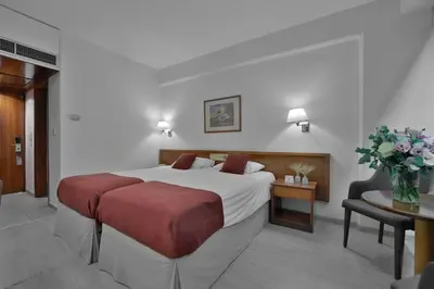 a hotel room with a large bed and a table at Odysseia Hotel Kapetanios in Limassol