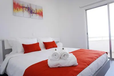 a bedroom with a large white bed with red pillows at Lazuli Sea View Beachfront Ap 43 in Larnaka