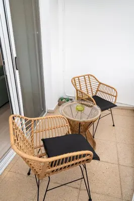 two wicker chairs and a glass table in a room at Lazuli Sea View Beachfront Ap 21 in Larnaka