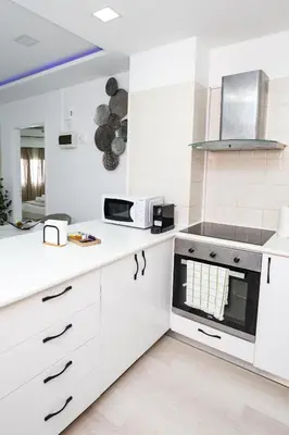 a white kitchen with white cabinets and a microwave at Lazuli Beach & Pool Apartment 501 in Larnaka