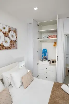 a bedroom with a white bed and a closet at Lazuli Beach & Pool Apartment 501 in Larnaka