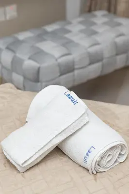 a white towel sitting on top of a bed at Lazuli Beach & Pool Apartment 501 in Larnaka