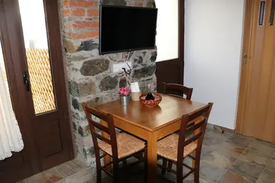 a wooden table with chairs and a television on a stone wall at AgroSpito Traditional Guest House in Agros