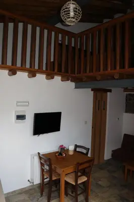 a dining room with a table and a tv on the wall at AgroSpito Traditional Guest House in Agros