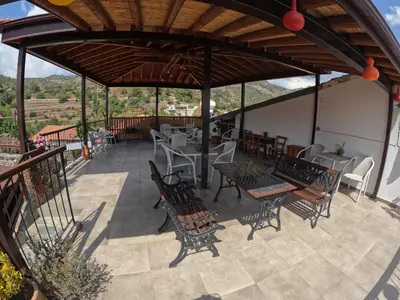a patio with tables and chairs under a wooden roof at AgroSpito Traditional Guest House in Agros