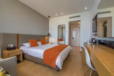 a hotel room with a bed with orange pillows at Crystal Springs Beach Hotel in Protaras