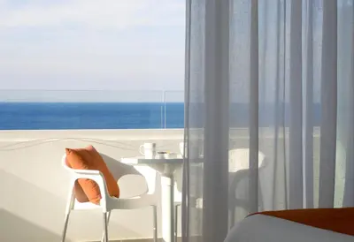 a room with a bed and a white chair and a window at Crystal Springs Beach Hotel in Protaras