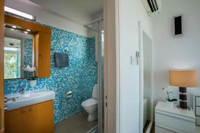 a bathroom with a toilet and a sink with blue tiles at Villa Ricky in Protaras