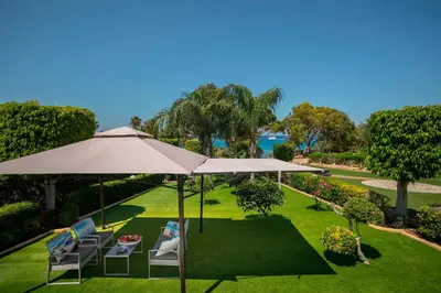 a patio with an umbrella and chairs on the grass at Villa Ricky in Protaras