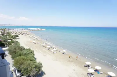 a beach with umbrellas and cars parked on it at Lazuli Sea View-Beachfront Ap 405 in Larnaka