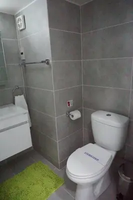 a bathroom with a white toilet and a green rug at Lazuli Sea View-Beachfront Ap 405 in Larnaka