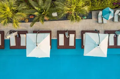 an overhead view of two white umbrellas next to a pool at Nestor Hotel in Ayia Napa