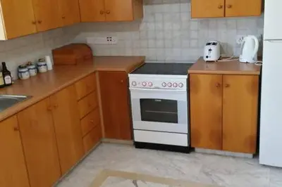 a kitchen with a white stove and wooden cabinets at Larnaka Beach House 3 in Larnaka