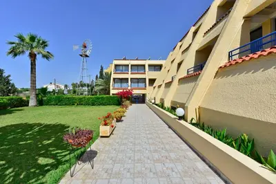 a walkway next to a building with a palm tree at Napa Prince Hotel Apts in Ayia Napa