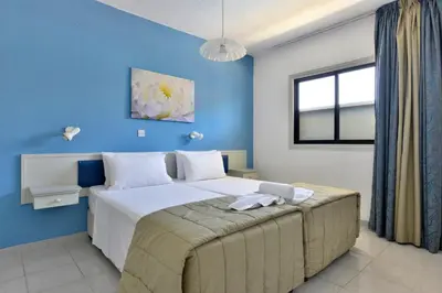 a bedroom with a large bed with a blue wall at Napa Prince Hotel Apts in Ayia Napa