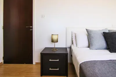 a bedroom with a bed and a night stand with a lamp at Seaside Luxury Flat Pervolia in Pervolia