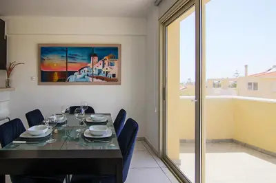 a dining room with a table with chairs and a painting at Seaside Luxury Flat Pervolia in Pervolia