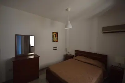 a bedroom with a bed and a dresser and a mirror at Krasas Beach Flats in Larnaka