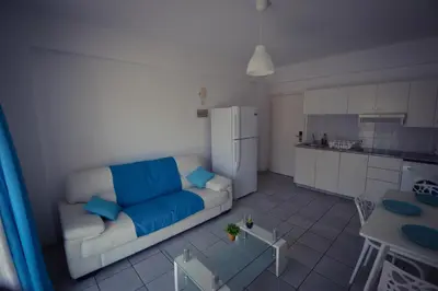 a living room with a couch and a kitchen at Krasas Beach Flats in Larnaka
