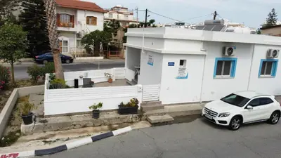 a white car parked in front of a white house at Apollo Rooms by Albert's Apartment in Larnaka