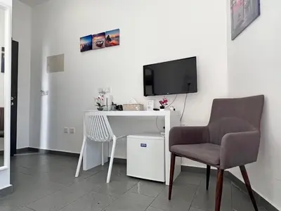 a room with a desk and a tv and a chair at Apollo Rooms by Albert's Apartment in Larnaka