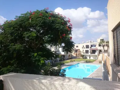 a tree with red flowers next to a swimming pool at Theodoros Apt. 408 in Protaras