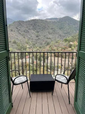 a table and two chairs on a balcony with a view at Theoxenia in Kalopanayiotis
