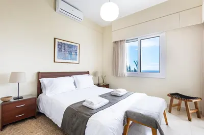 a bedroom with a bed with white sheets and a window at Villa Chrysta in Ayios Theodhoros