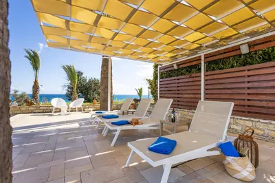 a patio with white chairs and a yellow umbrella at Villa Chrysta in Ayios Theodhoros