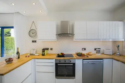 a kitchen with white cabinets and a clock on the wall at Protaras Villa Loulla in Protaras