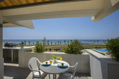 a table and chairs on a balcony with a view of the ocean at Larnaca Sunshore Beachfront Suite in Voroklini
